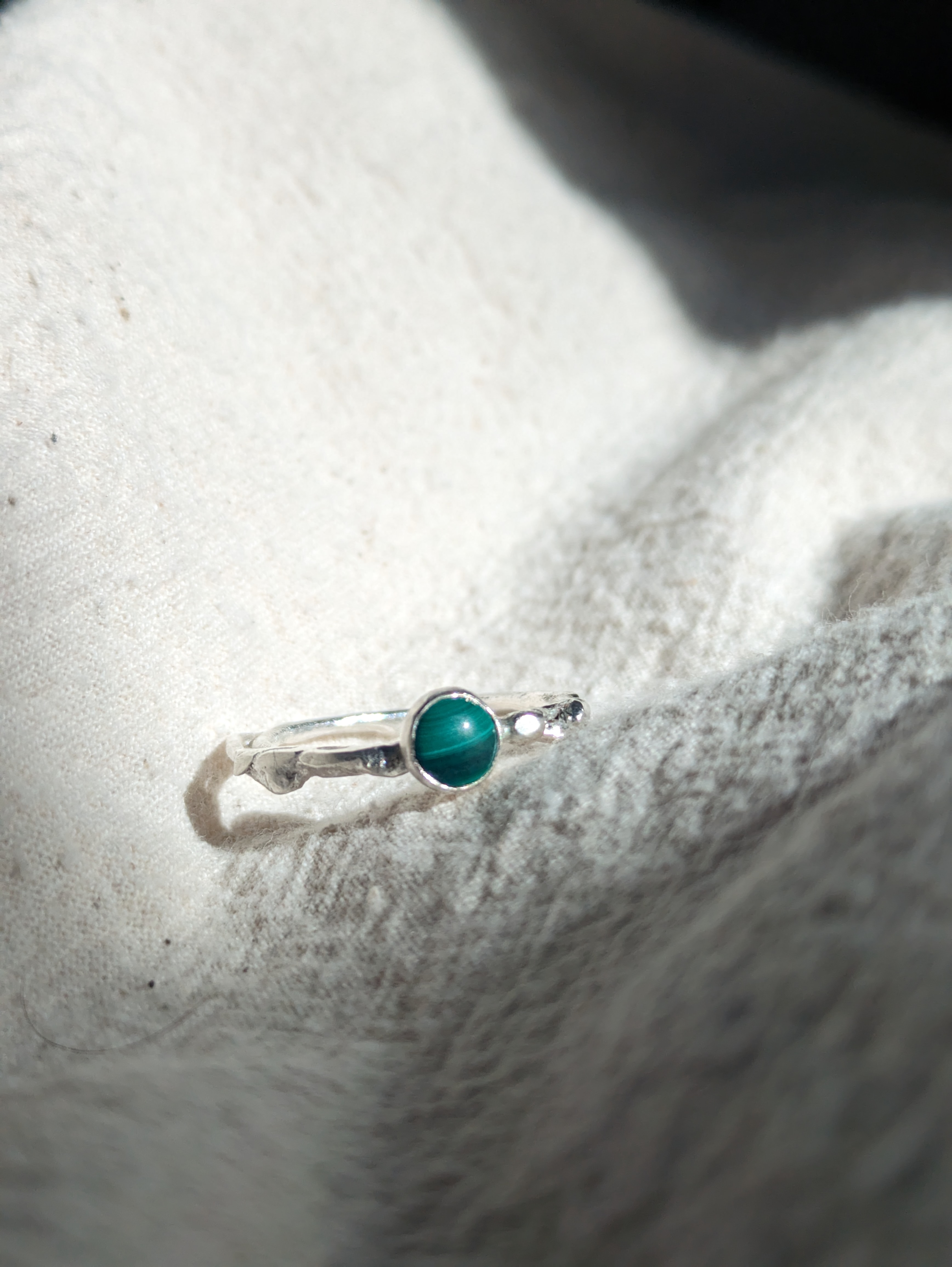 a molten sterling silver ring with a green striped malachite stone set into it