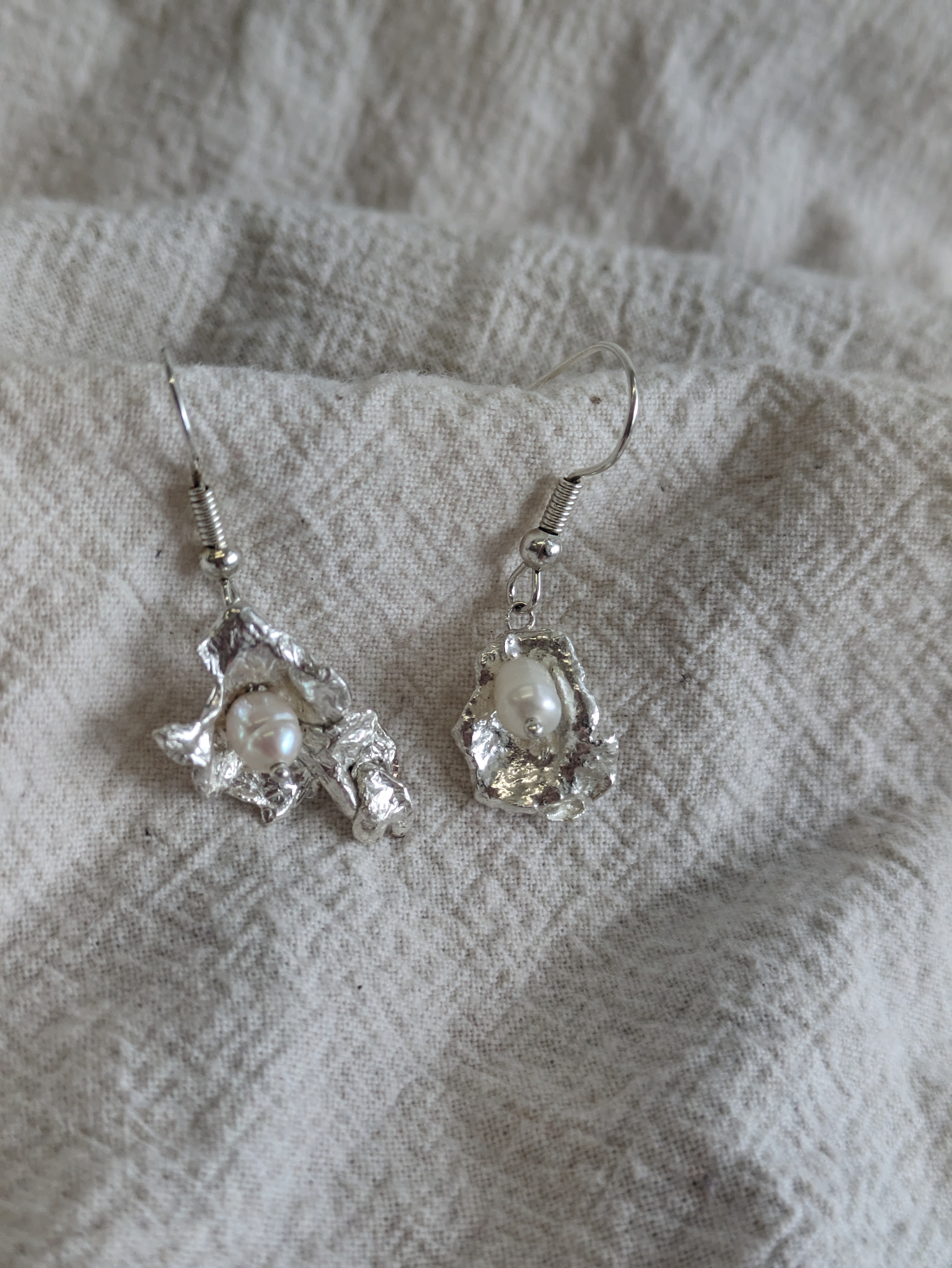 a pair of earrings made with molten splashes, a fresh water pearl in each to make them look like oysters