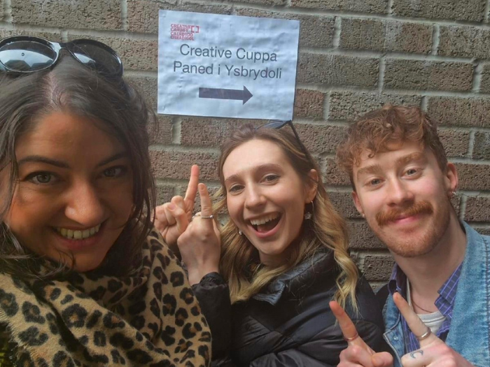 An image of the Creative Cardiff Team in front of a sign that says 'Creative Cuppa'