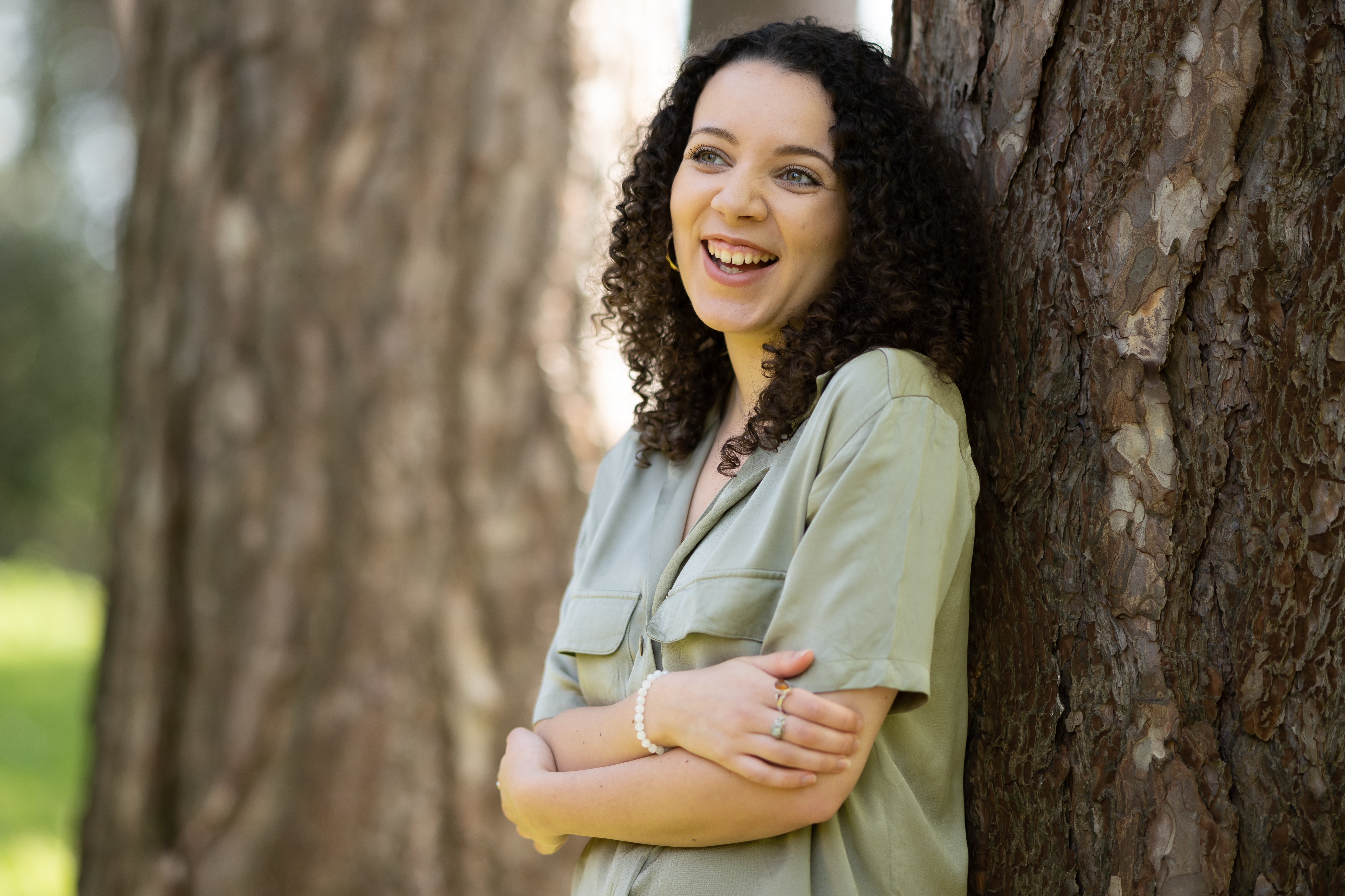 Taylor Edmonds - the new Future Generations Commissioner for Wales' poet in residence - stands against a tree with arms folded