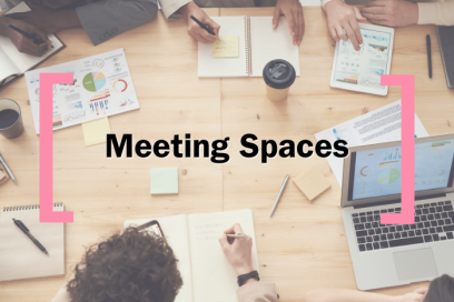 A faded background of an overhead desk shot, over which text reads 'Meeting Spaces' in between the Creative Cardiff Brackets in Pink