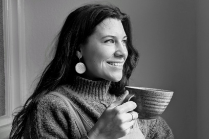 A black and white photo of a person with long hair holding a ceramic cup.