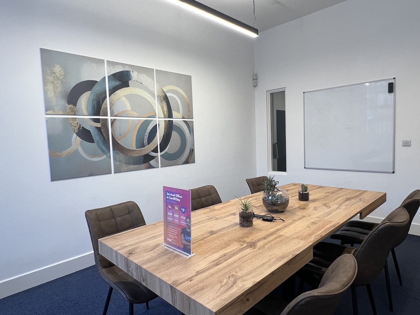 An image of a meeting room in West Bute House showing a long table with six chairs and a white board on the wall